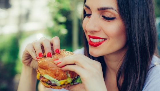 Junge Frau beißt gleich in einen Burger.