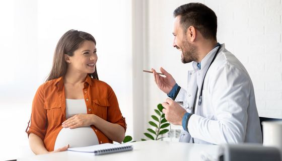 Eine schwangere Frau lässt sich von einem Arzt beraten.