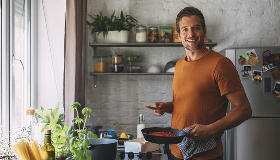 Junger Mann kocht in der Küche.