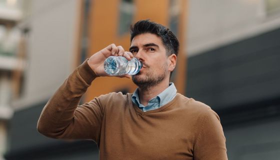 Junger Mann trinkt Wasser aus einer Plastikflasche.