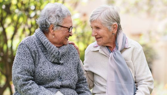 Zwei ältere Damen auf einer Bank, ins Gespräch vertieft.