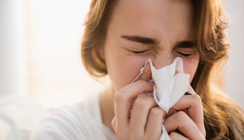 Frau putzt sich die Nase.