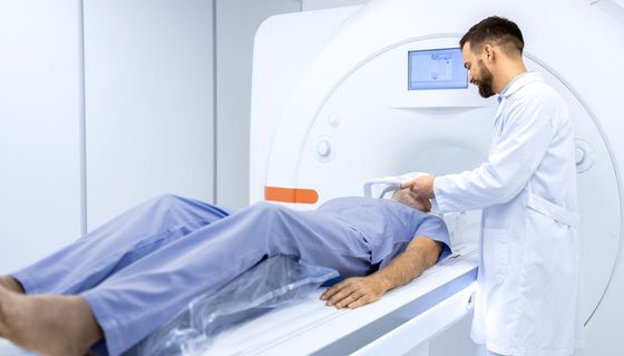 Medizinisches Fachpersonal bereitet einen Mann auf seinen MRT-Scan vor.