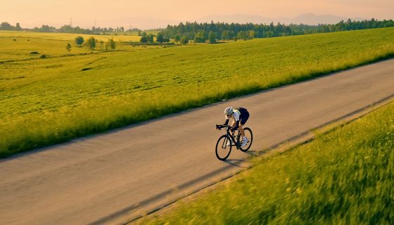 Ein Mann fährt auf einem Rennrad über eine unbefahrene Landstraße in schöner Landschaft.