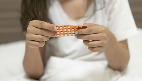 Eine Frau hält mit ihren Händen einen Monatsblister von der Minipille in der Hand.